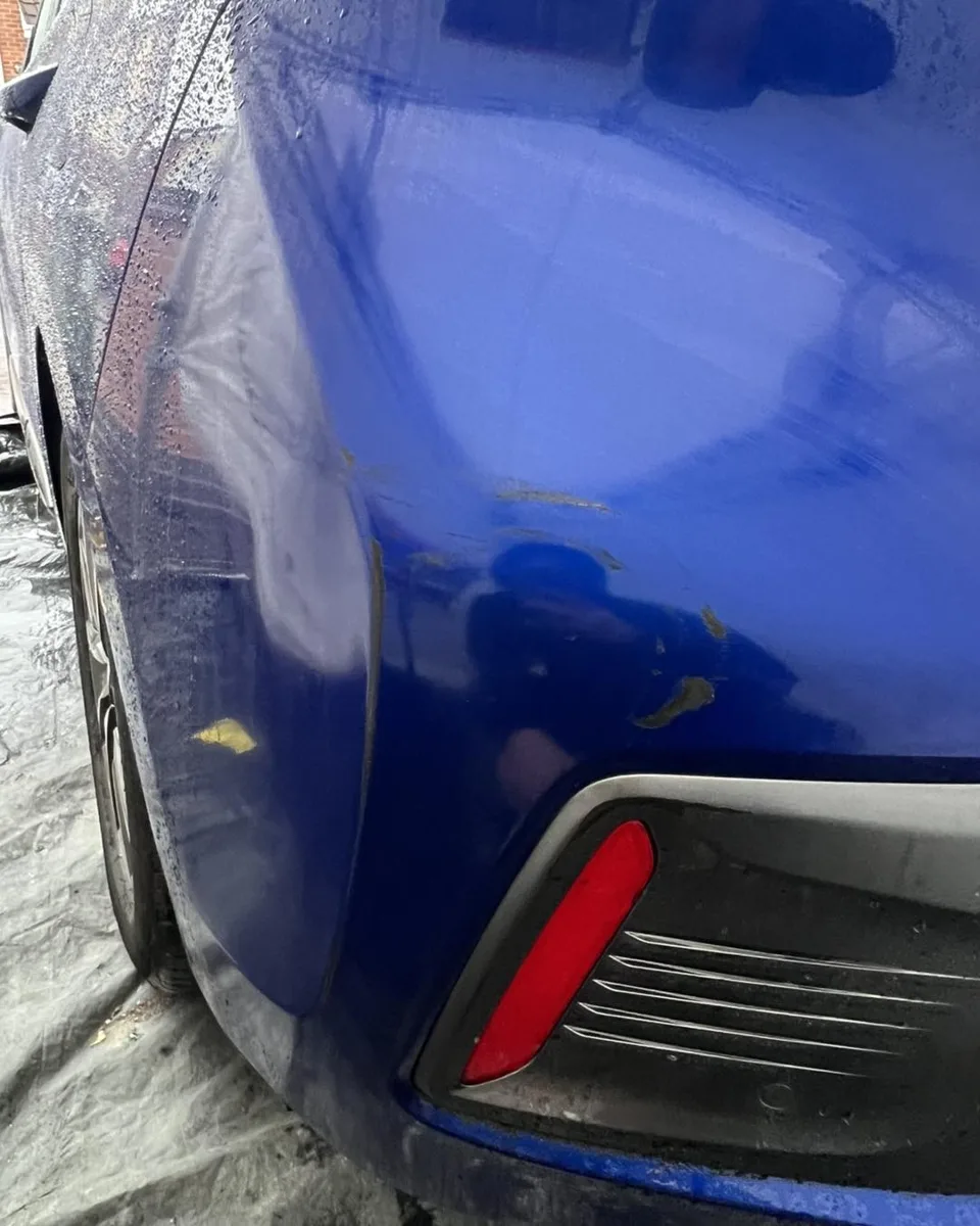 Scratched blue Hyundai rear bumper beside the reflector